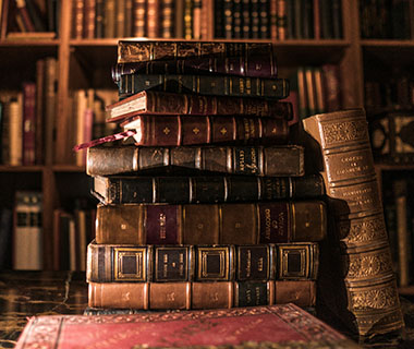 A pile of leather bound books is on a table