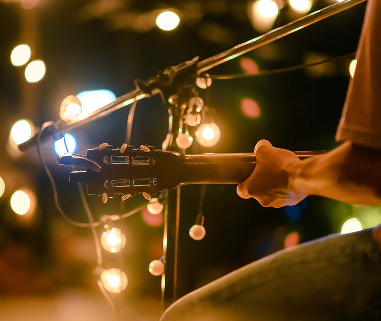 Close up rear view of man sitting playing acoustic guitar