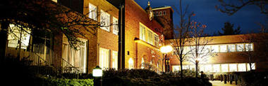 Night photograph of the university entrance with lights shining through the windows