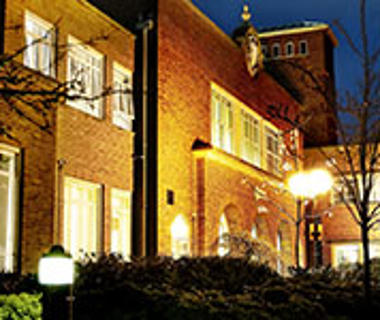 Night photograph of the university entrance with lights shining through the windows