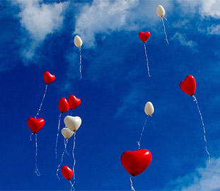 red and white heart-shaped balloons in a blue sky